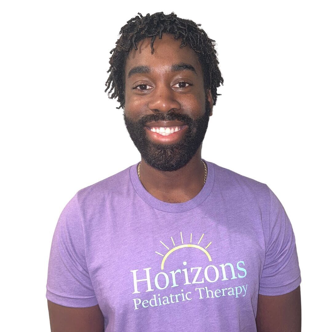 A man in purple shirt smiling for the camera.